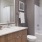 Large well lit bathroom with large mirror and brown cabinets 